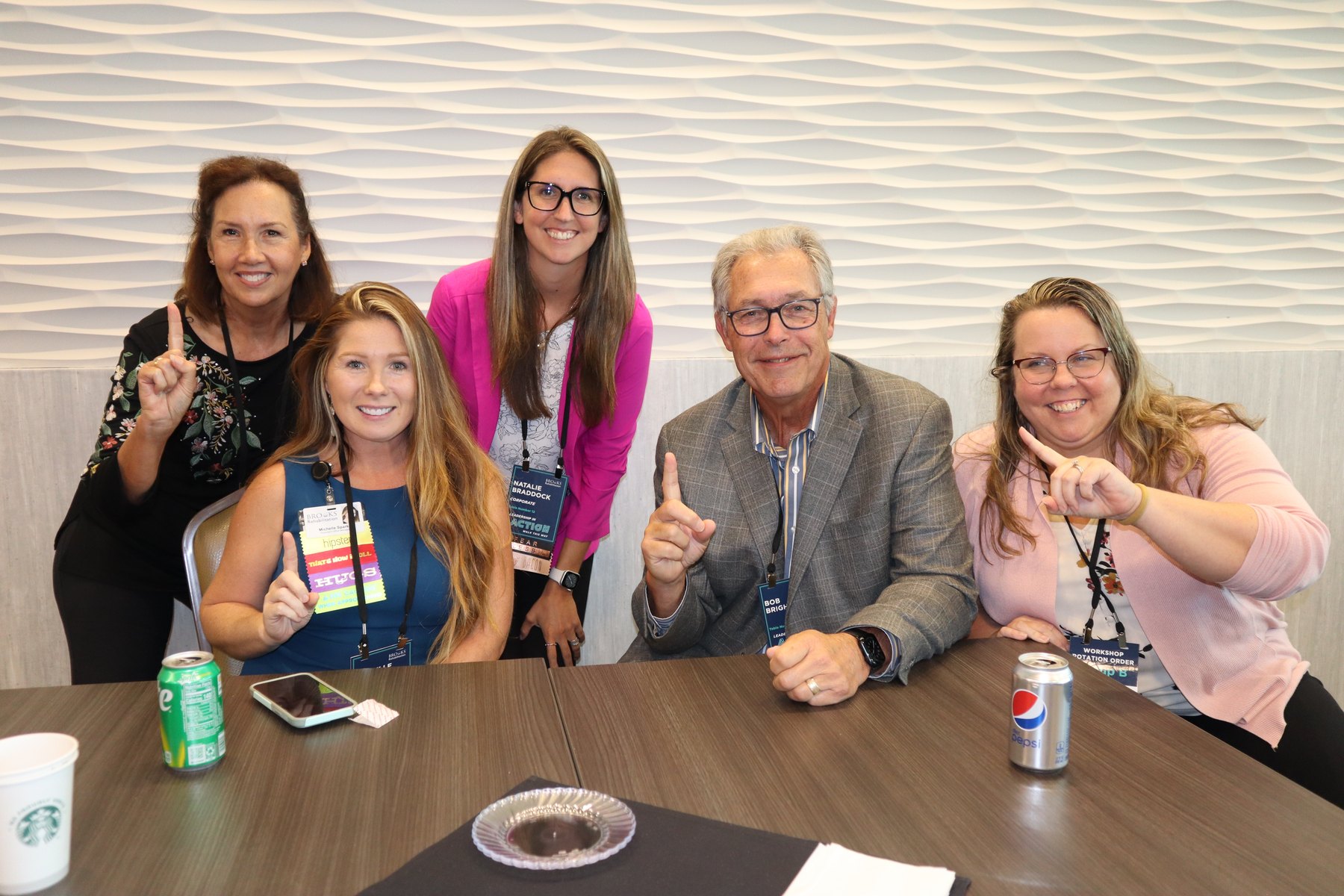 Corporate team at a conference table holding up number one after winning a trivia round