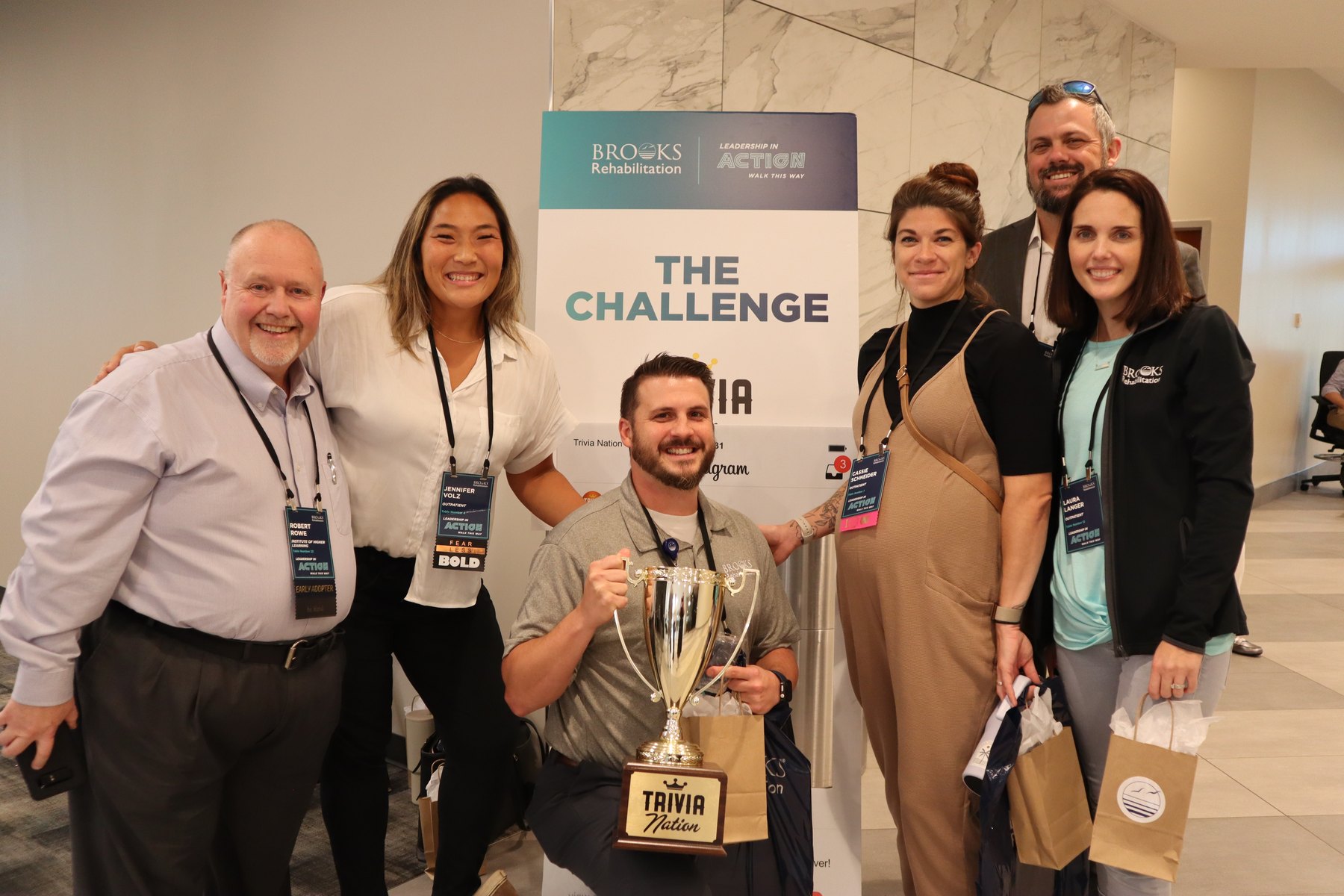 Leadership team posing with the Trivia Nation trophy at a Brooks Rehabilitation leadership challenge